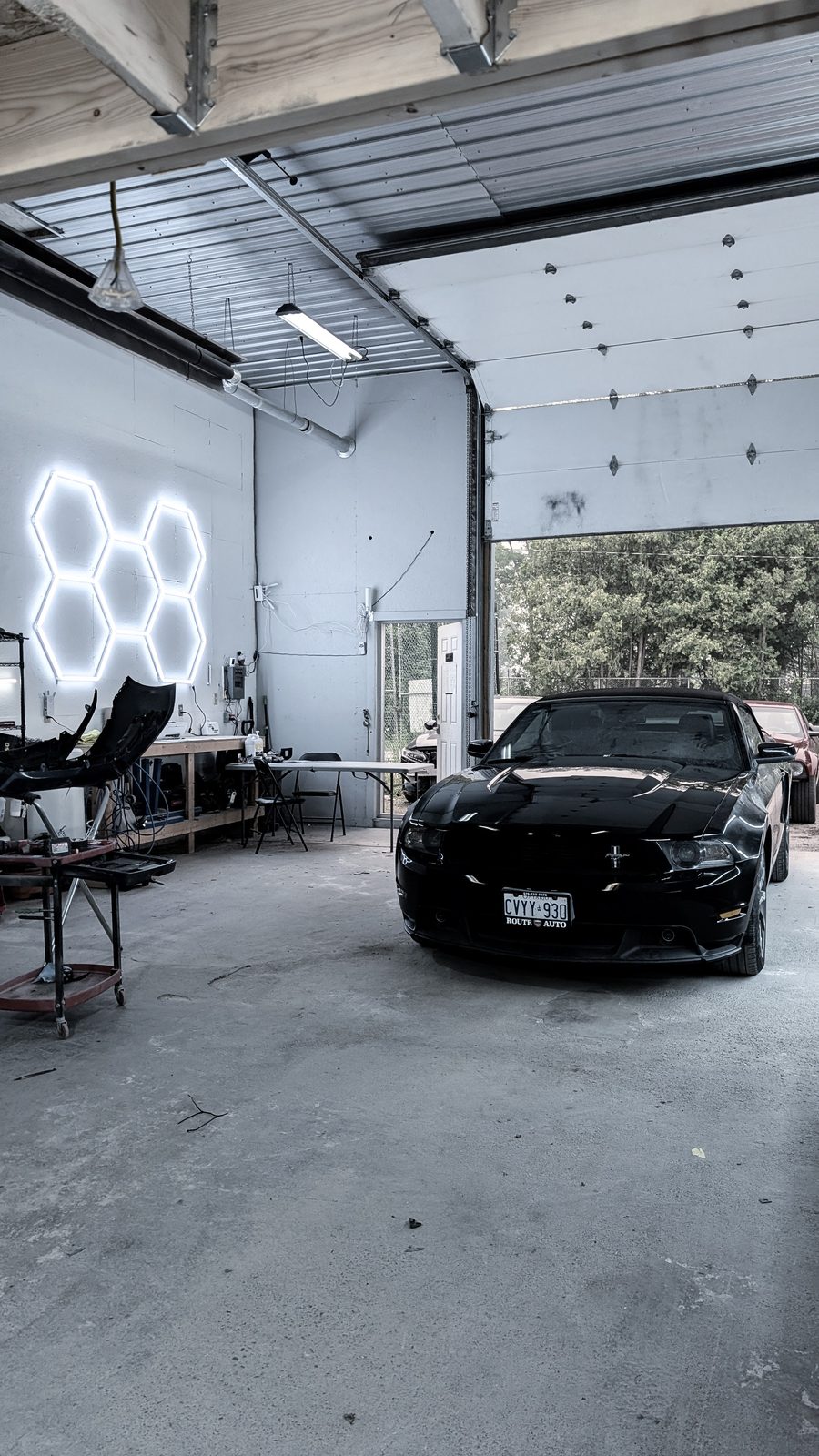 Black sports car under The Hive's hexagon neon signs